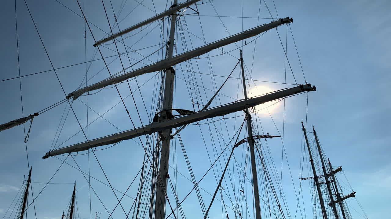 Pan across the rolled up sails and rigging of a sailboat in the dock.
