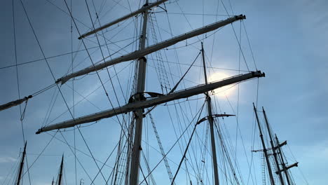 pan across the rolled up sails and rigging of a sailboat in the dock.