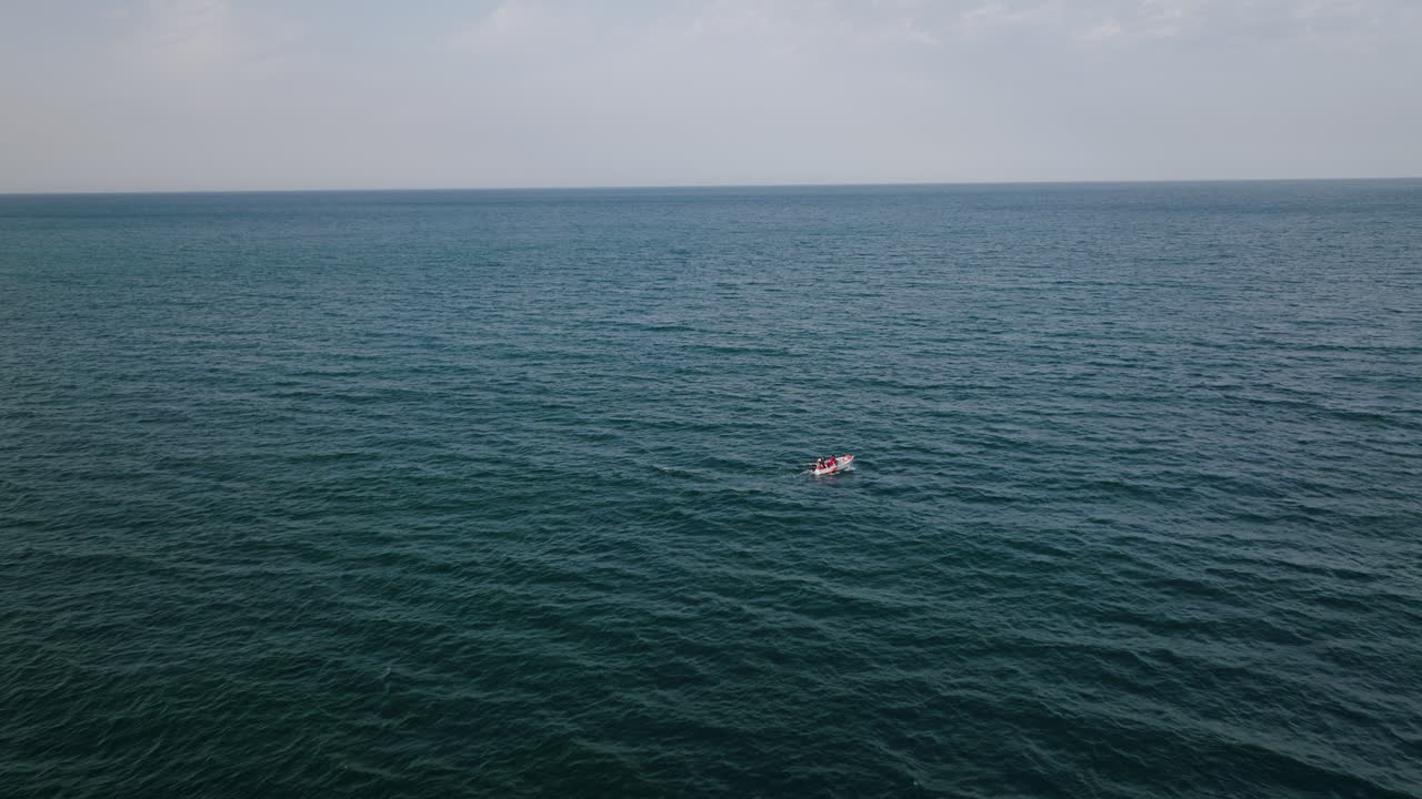 una toma aérea de seguimiento rápido persiguiendo un pequeño bote que está en el mar frente a la costa de bari, italia
