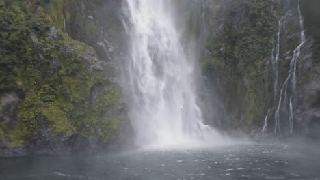 una cascada estruendosa que cae por la ladera de una montaña en un día húmedo y lluvioso en milford sound, nueva zelanda