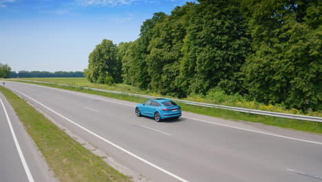 Presentation of luxury electric car. Blue automobile moving on a road on beautiful green nature background. View from above.