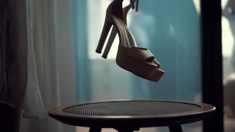 a bride lifting her wedding shoe hills off a wooden table