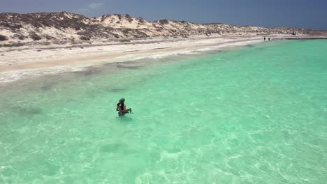 Ein-Unterwasserfotograf,-Der-Im-Kristallklaren,-Kabbeligen-Wasser-Spazieren-Geht