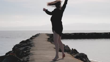 woman walks barefoot and spins around several time on cement pier