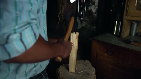 close up of unrecognizable man chopping small firewood with axe in cabin