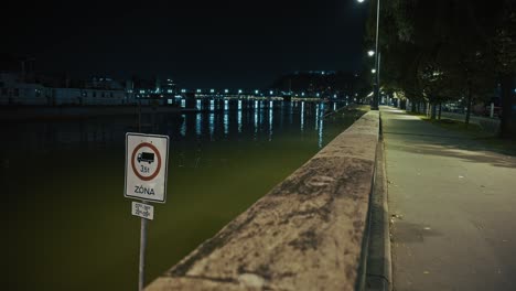 flooded riverside pathway at night with a traffic restriction sign partially submerged