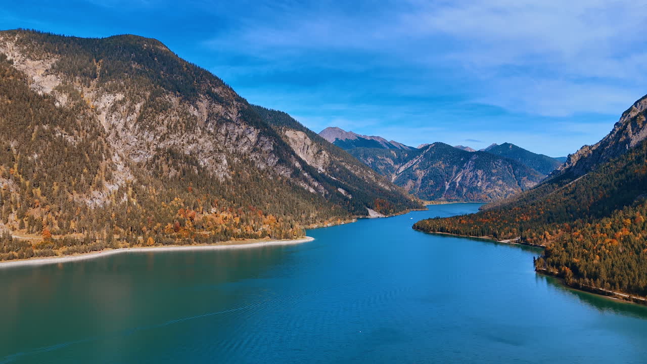 Flying above the beautiful azure calm waterscape of Lake Plansee in the Alps. Jaw-dropping panorama of unspoiled nature of Tyrol, Austria. Aerial view.