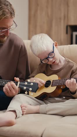 father teaching his son how to play ukulele