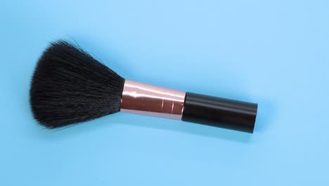 black makeup brush detail macro shot, rotating motion on blue surface background