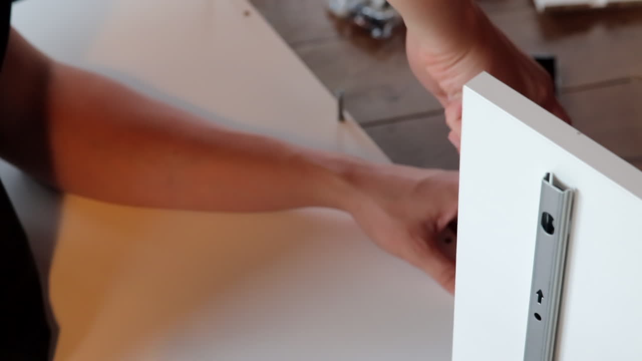 Primo piano della mano di un giovane ragazzo, che assembla uno scaffale in kit