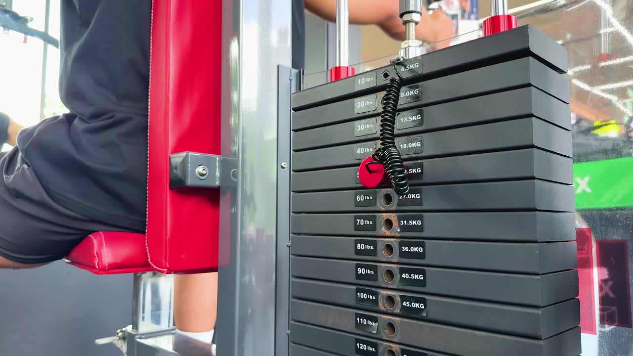 A person performs chest fly exercises on a machine in a brightly lit gym, showcasing strength and focus