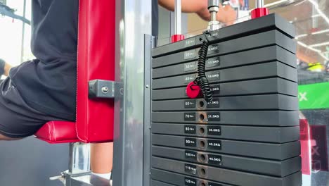 a person performs chest fly exercises on a machine in a brightly lit gym, showcasing strength and focus