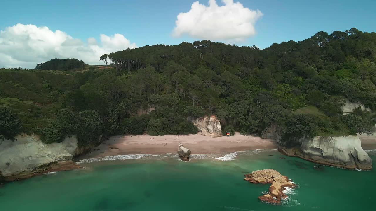 vuelo panorámico cinematográfico hacia la pared rocosa de cathedral cove, nueva zelanda