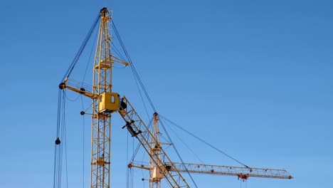 two construction cranes against the sky background.