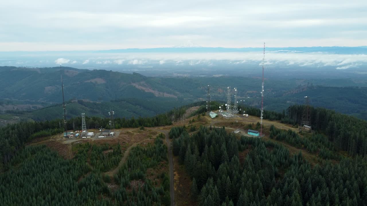 US, WA, Olympia, 2025-10-31 - Drone view of the radio towers at Capitol Peak outside the city. With Mt Ranier in the far distance