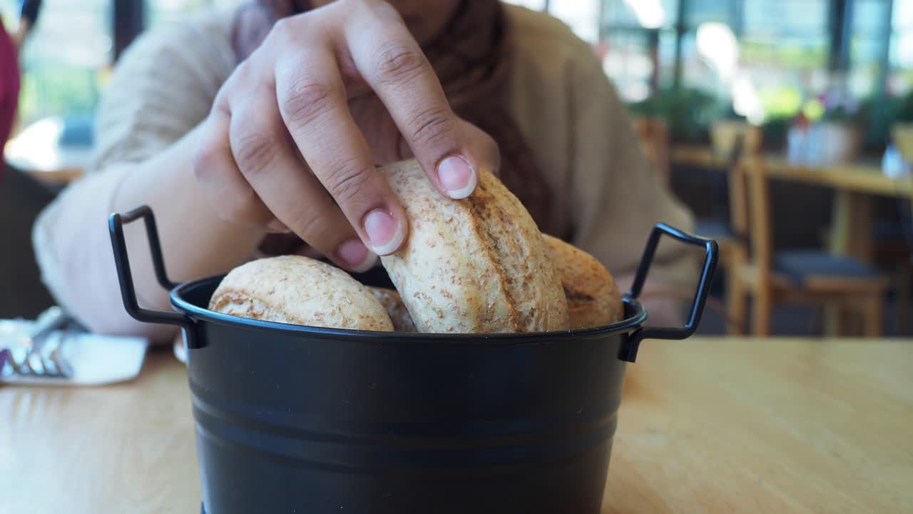 Woman Enjoying Fresh Bread Rolls at a Restaurant