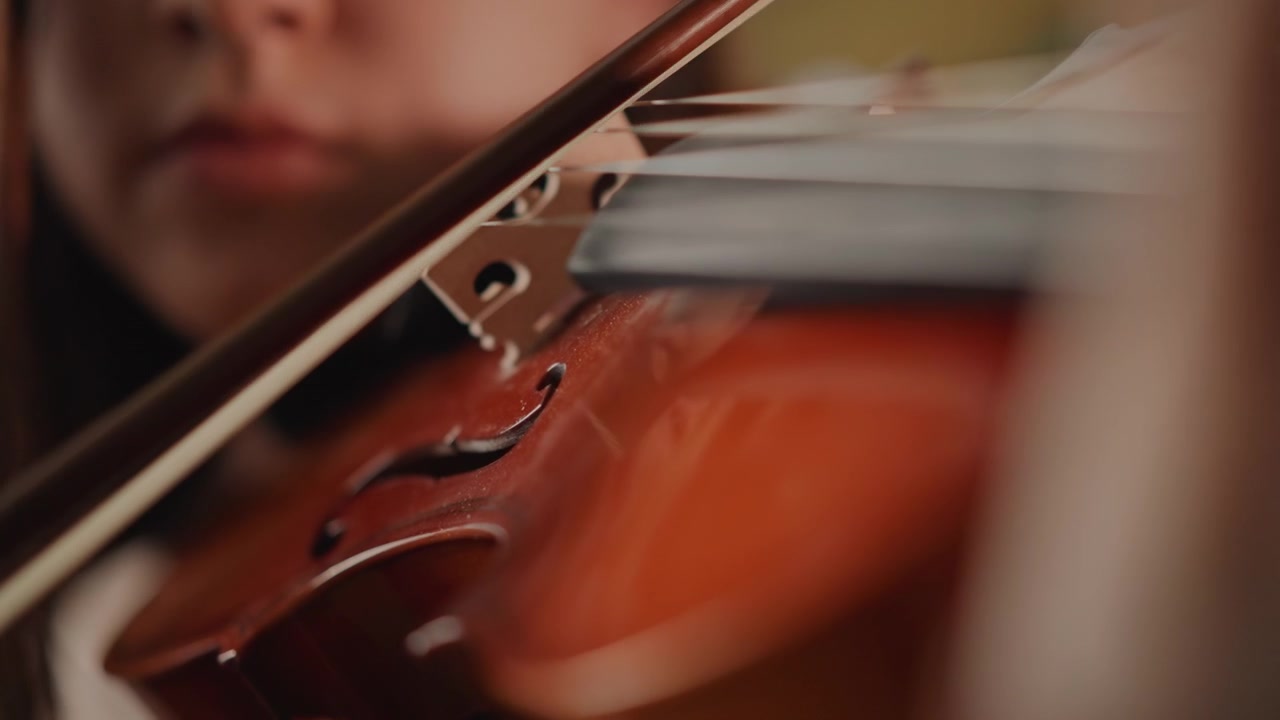 Student practices with gentle bowing. Closeup of fingers on instrument with coaching assistance visible. Detailed scene of student expertly maneuvering bow and fingers on violin under warm light