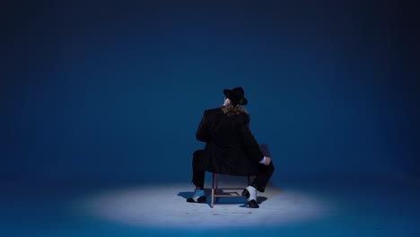 performer in a suit on a chair under spotlight