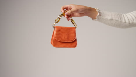 primer plano de una mujer influyente en las redes sociales produciendo contenido generado por el usuario sosteniendo un bolso de moda naranja 4