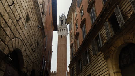 Picturesque-alley-with-historic-Siena-tower-in-Italy