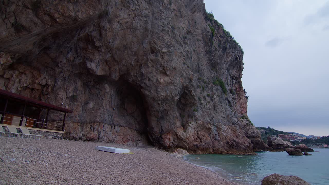 Static shot of white mattress on rocky beach in seaside cave in Taormina, Sicily, Italy (Sicilia, Italia), with a moody, minimalist White Lotus feel