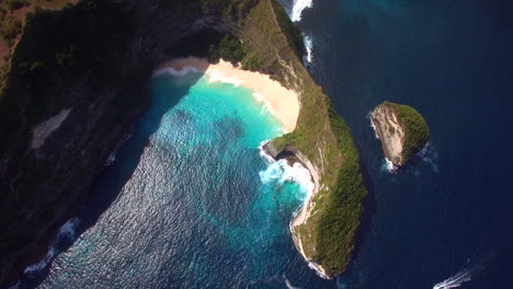 drone flying forward above the kelingking beach on nusa penida island green peninsula yellow sand