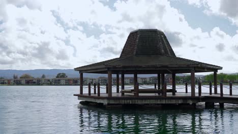 wooden gazebo by the lake and neighborhood in the background