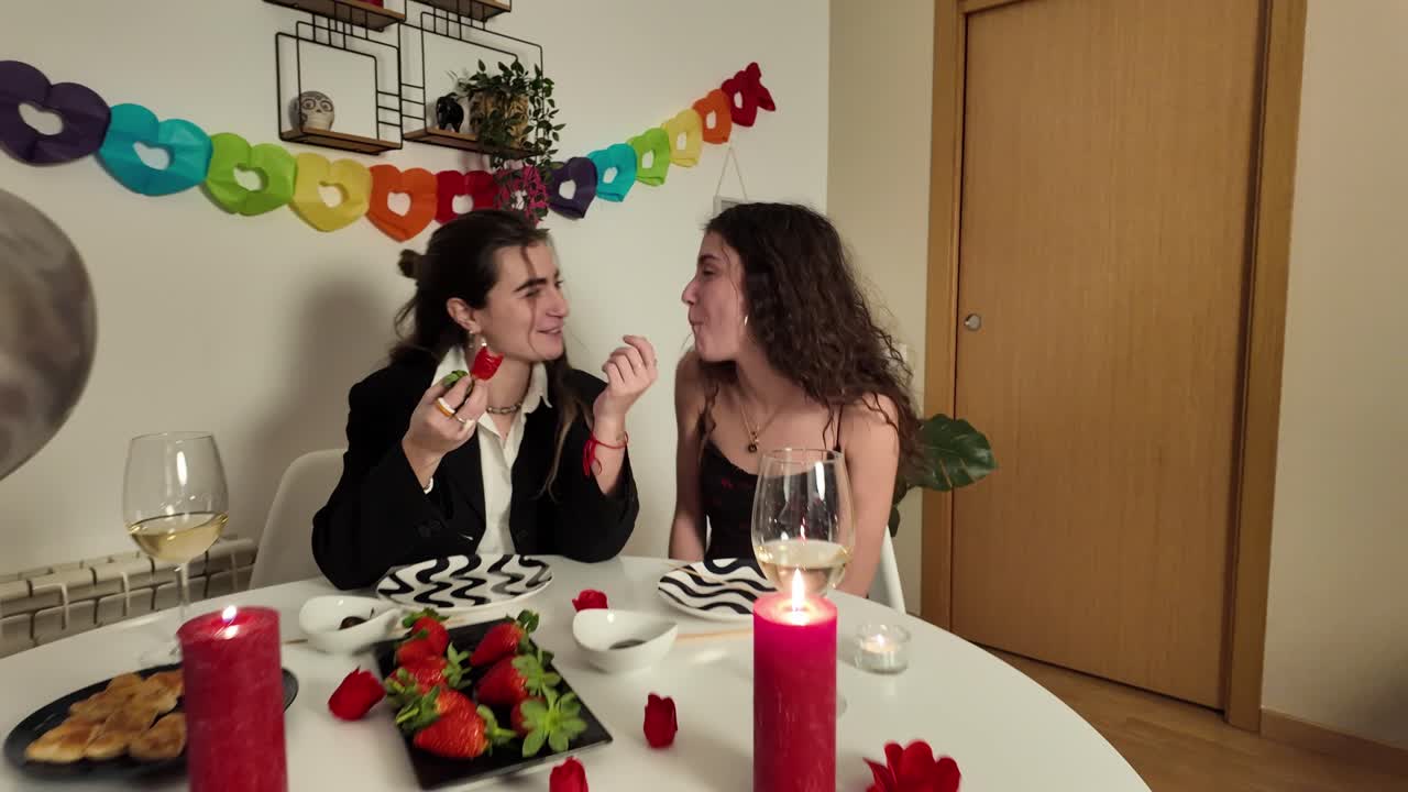 Two women eating strawberries at a table