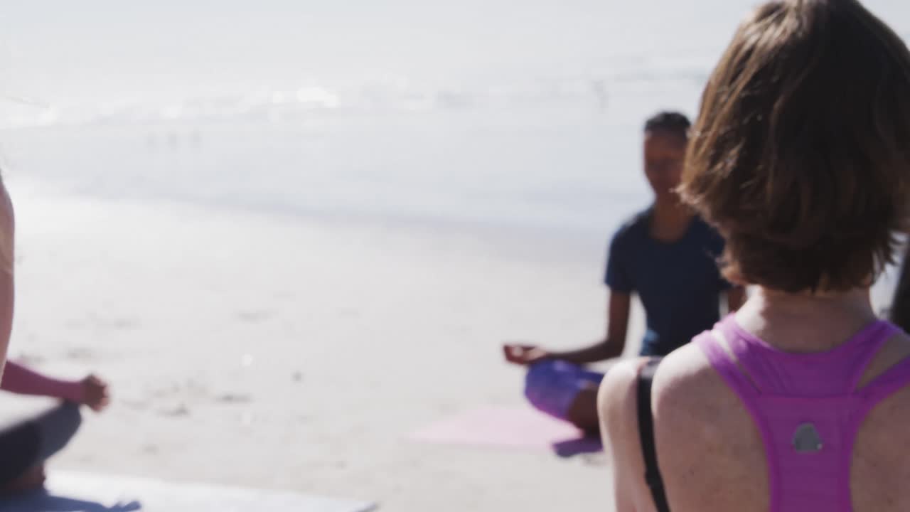 grupo multiétnico de mujeres haciendo yoga en la playa y fondo de cielo azul