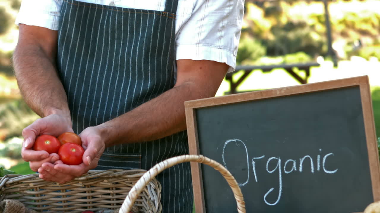 un granjero sonriente mostrando tomates en cámara lenta