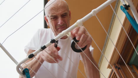 man repairs the clothesline with duct tape and a clip