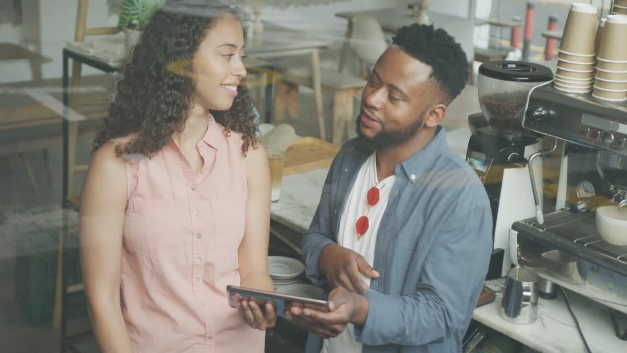 feliz propietario de café afroamericano y barista biracial usando un teléfono inteligente y hablando