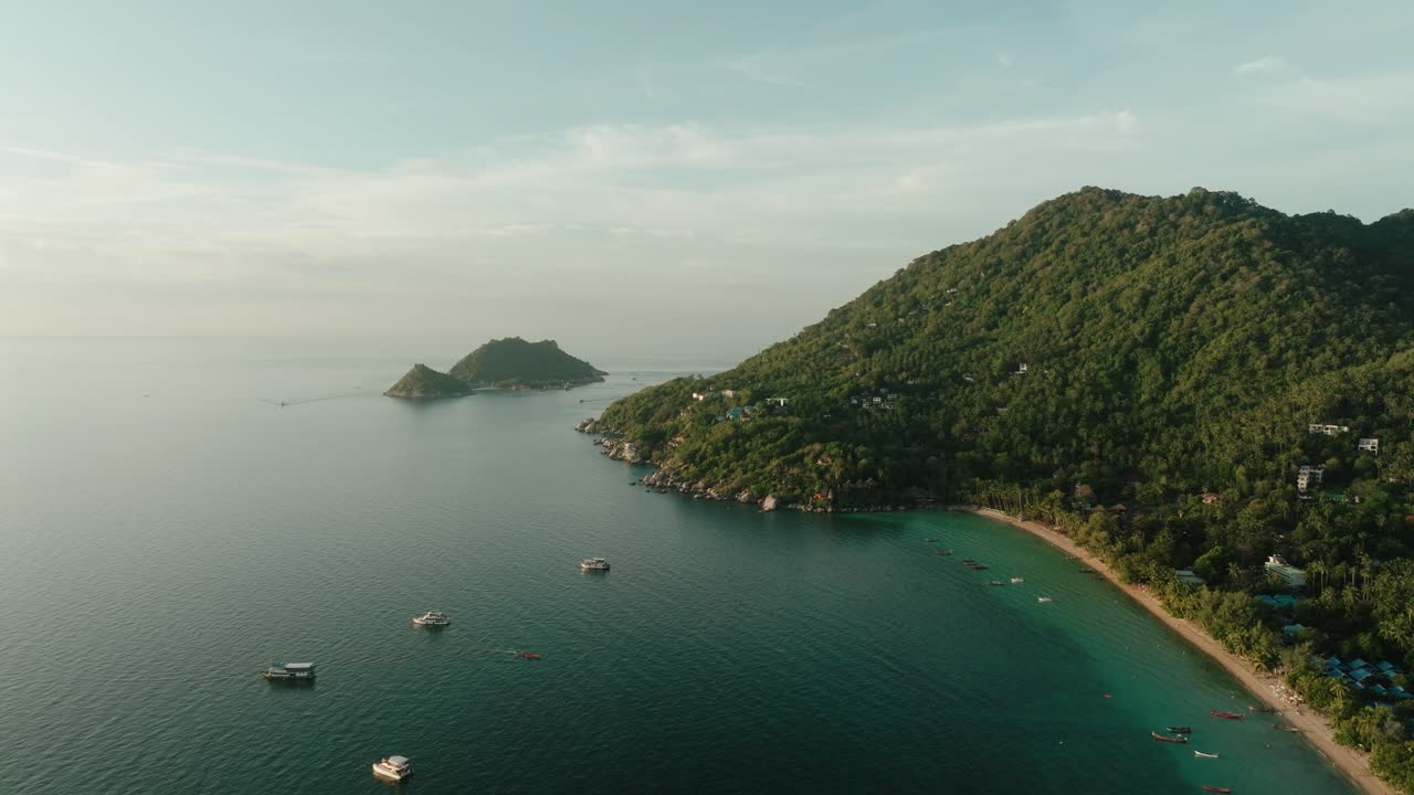 Boats anchored in Ko Tao, Thailand, with aerial view of coastline and green hills