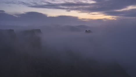 mountain range under floating clouds in morning time