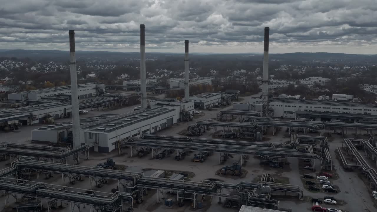 Aerial video of an industrial plant under cloudy skies, showcasing extensive piping and chimneys