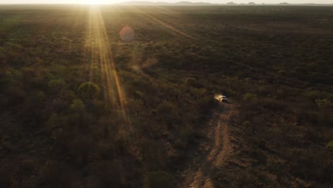 aerial shot of 4x4 truck climbing mountain at sunset.