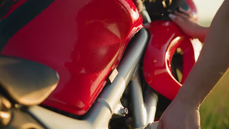 close-up of a hand carefully wiping the red and black fuel tank of a motorcycle with a cloth