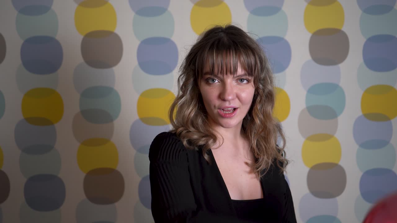 mujer joven bailando y sosteniendo globos en la mano contra un fondo colorido