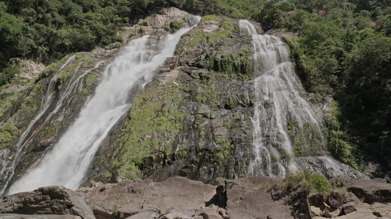 Low-angle shot of the cascading Okonotaki Waterfall on Yakushima Island, Japan. The powerful flow contrasts against rugged rocks covered in green moss, capturing the beauty of subtropical landscape.