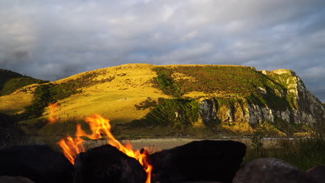 baja luz solar en las colinas alrededor de parakanui en la isla sur de nueva zelanda con una fogata encendida en primer plano