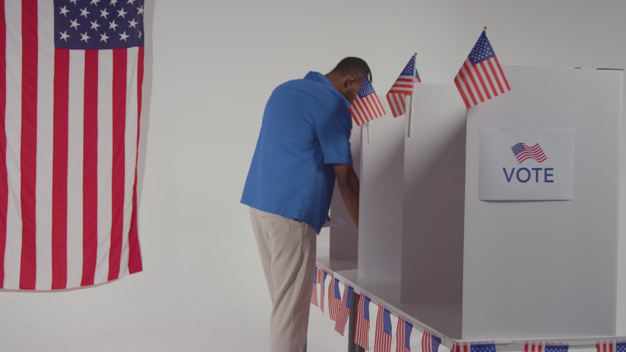 Man Walking Into Booth With Ballot Paper To Cast Vote In American Election