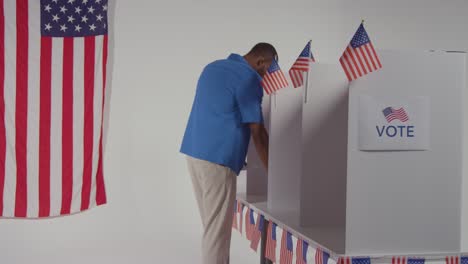 man walking into booth with ballot paper to cast vote in american election