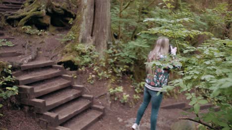 toma de órbita en cámara lenta de una fotógrafa tomando fotos del bosque en vancouver lynn valley