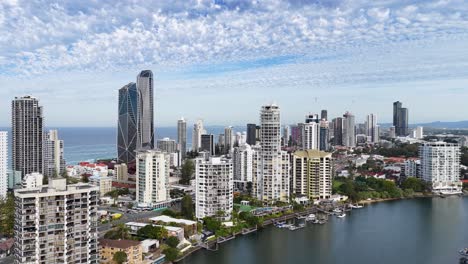 high-resolution aerial footage pans across gold coast’s modern skyline, waterways, and coastline under bright daylight with scattered clouds, showcasing urban architecture and natural beauty
