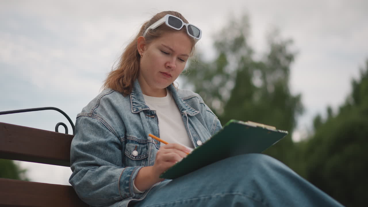 Fokusert student utendørs. Kvinne som studerer med konsentrasjon. Ung kvinne som leser flittig i utemiljøet. Bestemt kvinne fordyper seg i studiene i en rolig utendørs atmosfære.