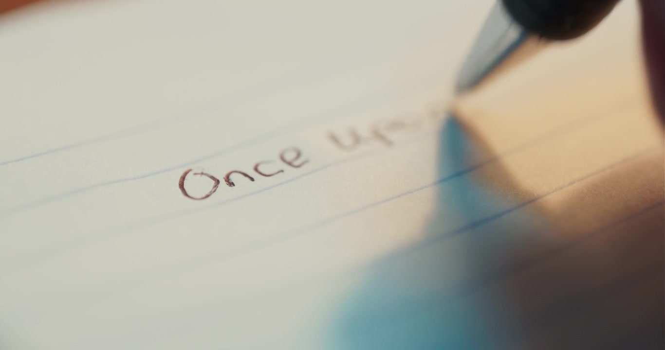 A macro shot of a black pen writing the words Once Upon a Time on lined paper, suitable for storytelling, literature, and creative education concepts.