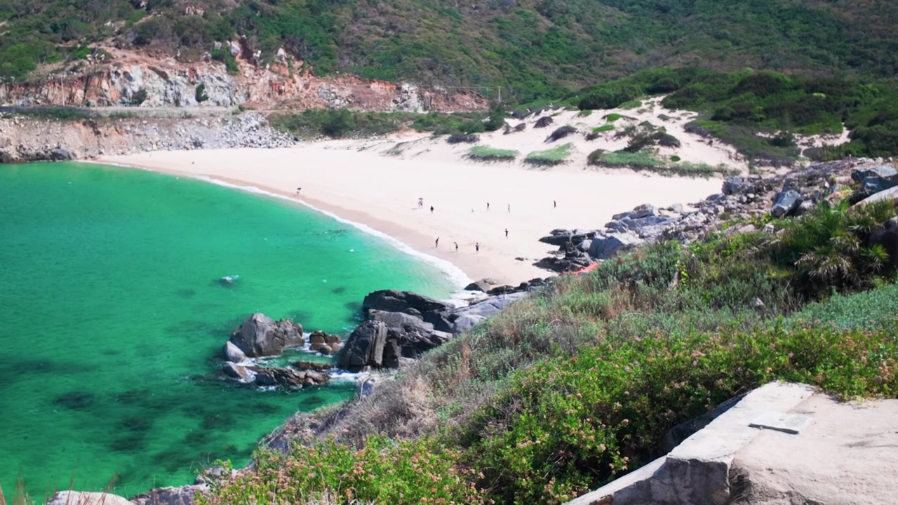 Um grupo de pessoas passa o tempo em uma praia em Dak Lak, Vietnã. Eles caminham na areia, nadam na água e se conectam com a natureza sob o sol.