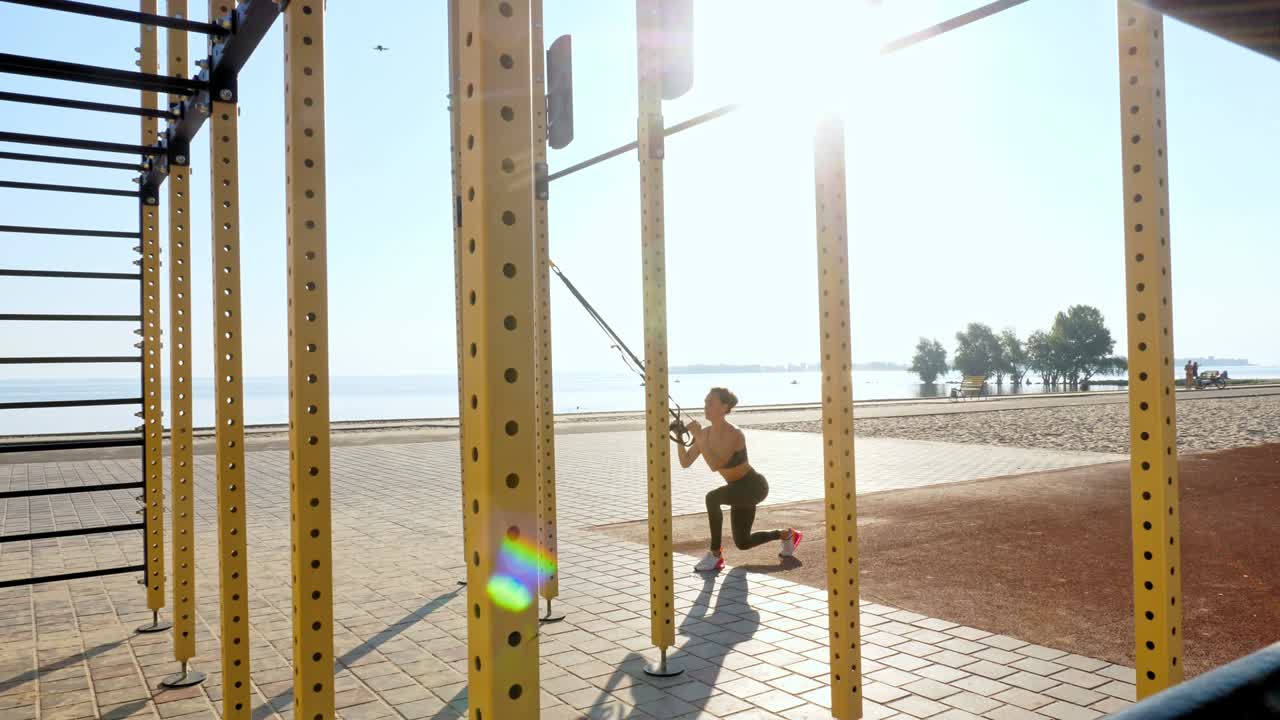 workout outdoors. suspension straps. workout with straps. Athletic young woman is doing all-body resistance exercises using looped ropes TRX, at the beach during sunset or sunrise. Fitness training outdoors. healthy lifestyle concept. morning sport