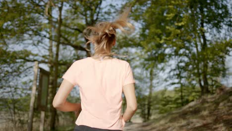Woman-running-through-trees-in-woods-on-sunny-day