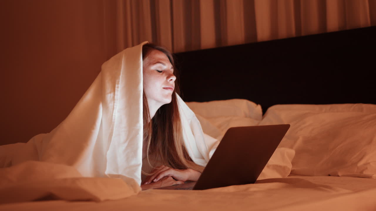 밤에 침대에서 노트북으로 일하는 여자